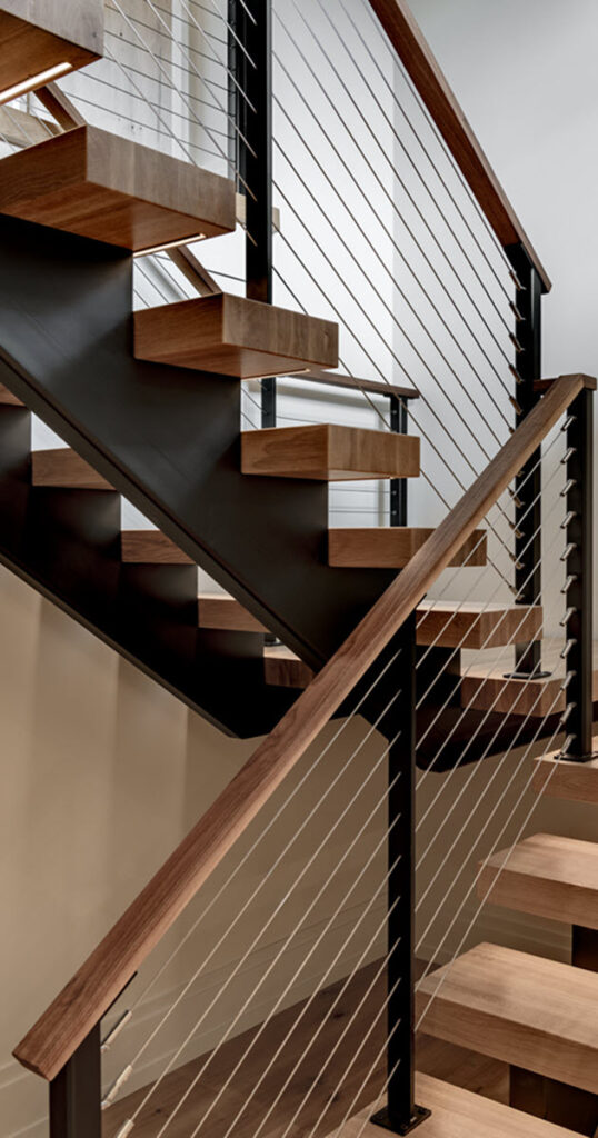 Doubele stringer steel staircase with wood treads and cable railings. The treads have unique concealed LED lighting