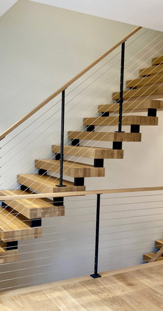 Hidden dual sringer stair with wood treads and wood handrail with cable railing.