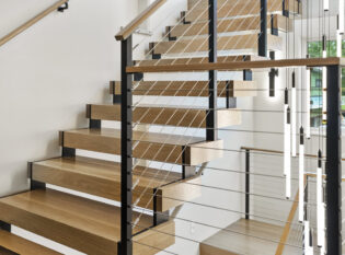 Cable railings on floating staircase with large chandelier