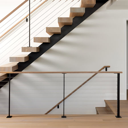 Floating stairs that feature wood treads and cable railings. The treads ar uniquely made to appear to slice into the stair stringer.