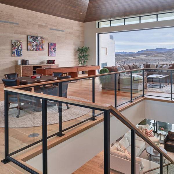 A metal framed glass railing with wood top rail traverses up the stairs and wraps the balcony. The top rail is wood and is finished to match the flooring that is open to the exterior decks.