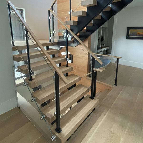 Glass railing with sleek metal posts on a double stringer staircase. White oak stair treads match the flooring and handrails. The double stringer stair conceals all the hardware for a minimalist appearance.